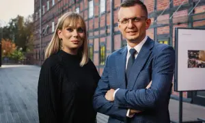 Dwoje prawników, kobieta i mężczyzna, pozuje przed ceglanym budynkiem.