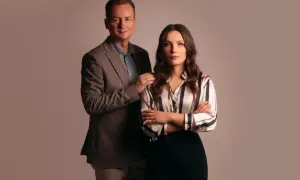 Mężczyzna w garniturze i kobieta w pasiناك bluzce stoją obok siebie.