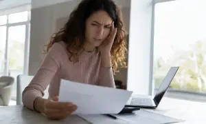 Zmartwiona kobieta analizuje dokumenty, być może dotyczące odrzucenia spadku przez małoletniego.