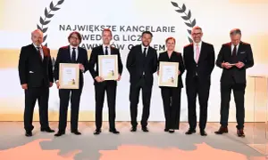 Sześć osób w garniturach odbiera nagrody na scenie.