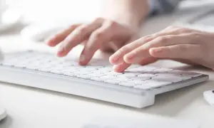 Dłonie piszą na klawiaturze. Dowiedz się, jak zrobić twardą spację w Wordzie, by tekst wyglądał profesjonalnie.