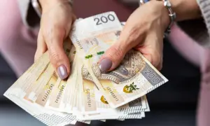 Dłonie trzymają stos banknotów 200 zł. Czy to zapowiedź sankcji kredytu darmowego?