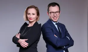 Kobieta i mężczyzna w strojach biznesowych stoją plecami do siebie, patrząc w stronę widza.