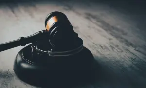 Młotek sędziowski i kajdanki na drewnianym blacie. Symbolizują sprawiedliwość i możliwość złożenia apelacji od wyroku.