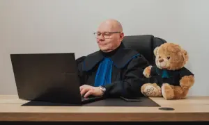 Sędzia z pluszowym misiem przy laptopie. Zastanawiasz się, ile kosztuje porada prawna u notariusza?