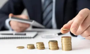 Dłoń kładzie monetę na rosnącej stercie, symbolizując zabezpieczenie alimentów i budowanie finansowej przyszłości.