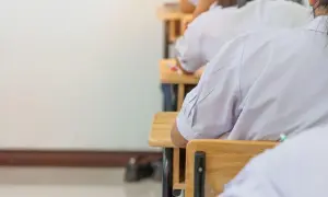 Uczniowie w białych koszulach siedzą w ławkach, skupieni na zadaniach. Może to być dzień, w którym marzą o zwolnieniu z egzaminu ósmoklasisty.