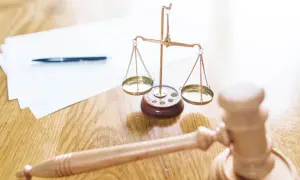 Młotek sędziowski, waga sprawiedliwości i dokumenty. Gdy słyszymy "odroczenie rozprawy co to znaczy", myślimy o tym, że sprawa będzie kontynuowana później.