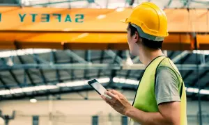 Pracownik w żółtym kasku i kamizelce odblaskowej z tabletem. Nad nim napis SAFETY. Jaki akt prawny reguluje podstawowe obowiązki pracodawcy w zakresie bhp?