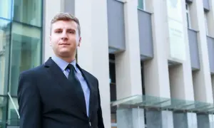 Mężczyzna w garniturze przed nowoczesnym budynkiem.