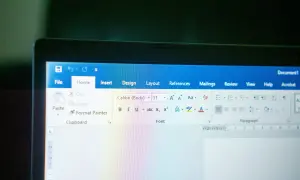 Ekran laptopa z otwartym edytorem tekstu. Widoczna jest wstążka z opcjami, w tym czcionka Calibri.