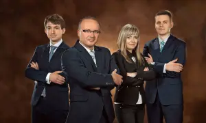 Cztery osoby w garniturach stojące z rękami skrzyżowanymi na piersi.