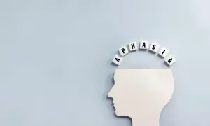 Biały profil głowy z literami tworzącymi słowo "APHASIA" nad nim. Obraz symbolizuje, co to jest afazja – trudności z mową i rozumieniem.