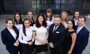 Grupa prawników w garniturach i strojach biznesowych pozuje przed budynkiem.