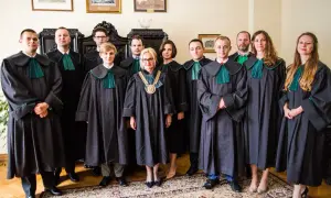 Grupa prawników w togach stoi w pomieszczeniu.