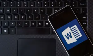 Smartfon z ikoną Worda leży na klawiaturze. Możesz kliknąć ten hiperłącze, aby otworzyć dokument.