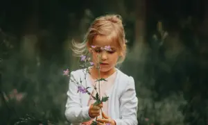 Dziewczynka z afazją u dzieci, trzymająca bukiecik polnych kwiatów.