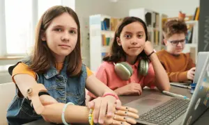 Dziewczynka z protezą ręki i jej rówieśnicy uczą się razem. To przykład edukacji włączającej, gdzie każdy ma szansę rozwijać się.