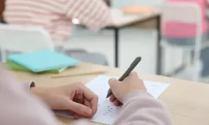Uczeń pisze test, skupiony na zadaniach. To ważny moment, jak egzamin dojrzałości.