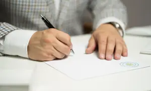 Mężczyzna w eleganckiej marynarce podpisuje dokument. To ważny odpis wyroku rozwodowego, który kończy pewien etap życia.