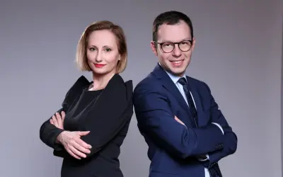 Kobieta i mężczyzna w strojach biznesowych stoją plecami do siebie, patrząc w stronę widza.
