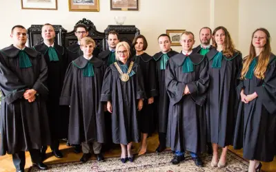 Grupa prawników w togach stoi w pomieszczeniu.