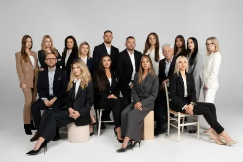 Grupa prawników i radców prawnych w eleganckich strojach pozuje do zdjęcia.