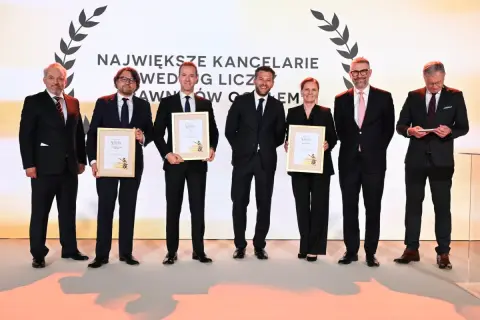 Sześć osób w garniturach odbiera nagrody na scenie.