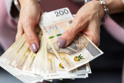 Dłonie trzymają stos banknotów 200 zł. Czy to zapowiedź sankcji kredytu darmowego?