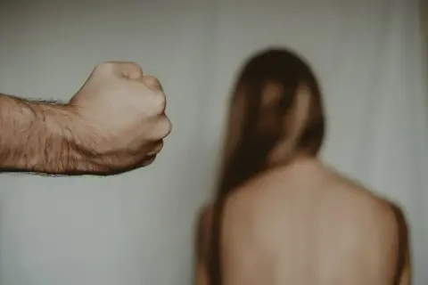 Zaciśnięta pięść mężczyzny grozi kobiecie. Gdzie zgłosić znęcanie psychiczne przez męża? Szukaj pomocy.
