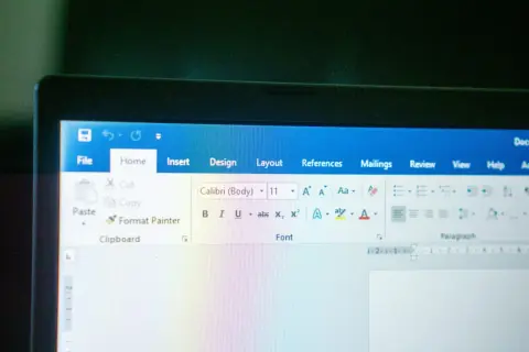 Ekran laptopa z otwartym edytorem tekstu. Widoczna jest wstążka z opcjami, w tym czcionka Calibri.