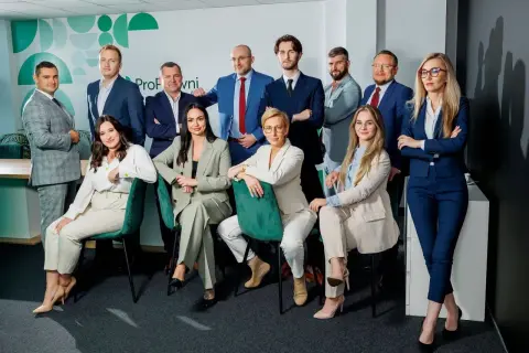 Zespół prawników w garniturach pozuje do zdjęcia w nowoczesnym biurze.