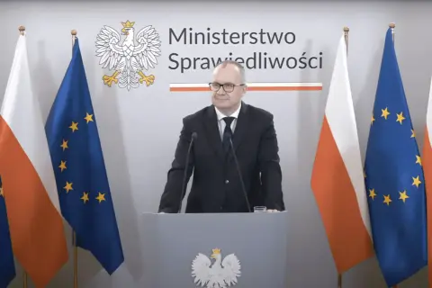 Minister sprawiedliwości przemawia na tle flag Polski i UE. Tematem dyskusji jest ustawa frankowa.