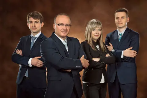 Zespół prawników w garniturach pozuje na brązowym tle.