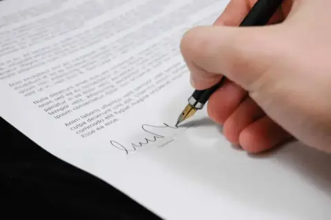 Dłoń podpisuje dokument, dokonując zrzeczenia się spadku.