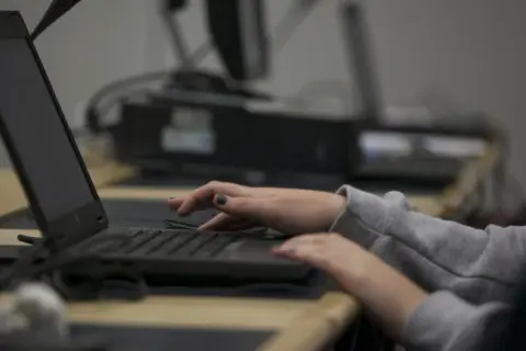 Dłonie piszą na klawiaturze laptopa, jakby w pośpiechu, jakby ktoś prowadził **stalking** w sieci.