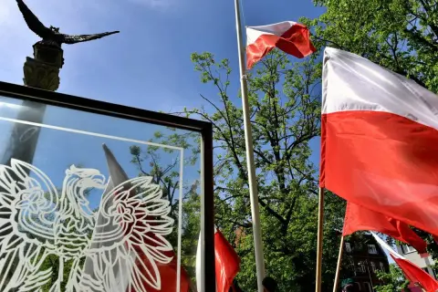 Orzeł biały i polskie flagi na tle nieba. Czy 3 maja można pracować? To pytanie zadają sobie Polacy w święto Konstytucji.