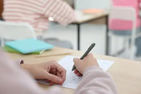 Uczeń pisze test, skupiony na zadaniach. To ważny moment, jak egzamin dojrzałości.
