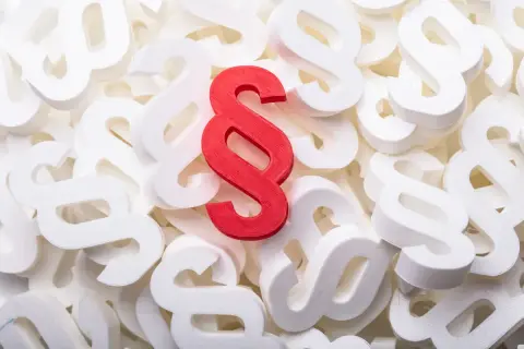 Czerwony symbol paragrafu wyróżnia się na tle białych, tworząc wizualizację ważnego przepisu prawnego.
