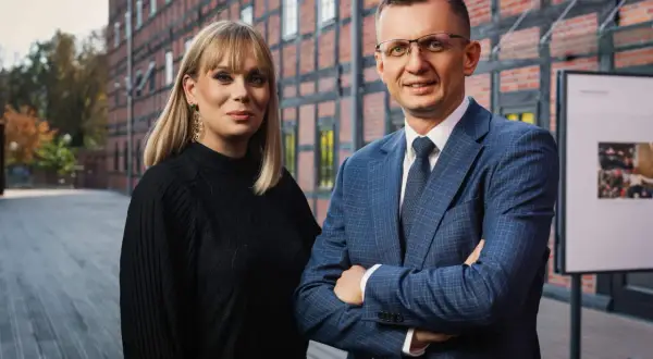 Dwoje prawników, kobieta i mężczyzna, pozuje przed ceglanym budynkiem.