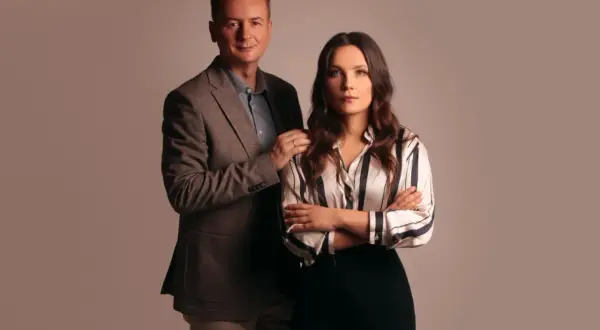 Mężczyzna w garniturze i kobieta w pasiناك bluzce stoją obok siebie.