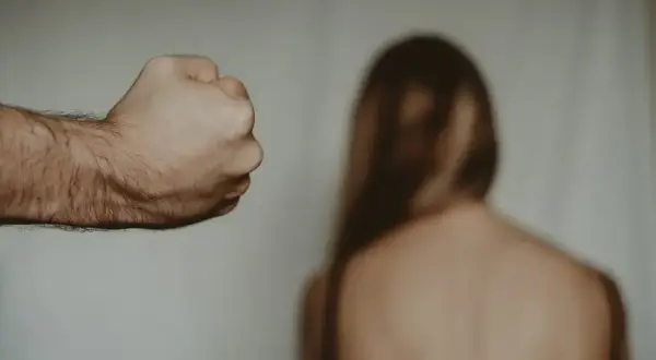 Zaciśnięta pięść mężczyzny grozi kobiecie. Gdzie zgłosić znęcanie psychiczne przez męża? Szukaj pomocy.