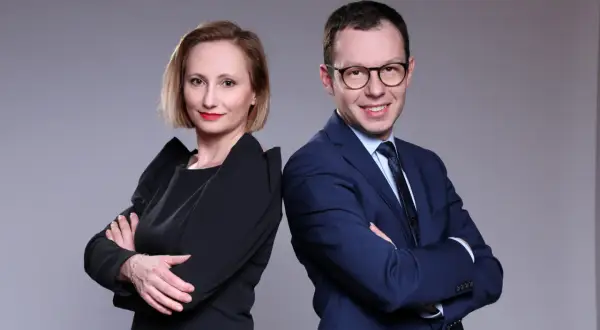 Kobieta i mężczyzna w strojach biznesowych stoją plecami do siebie, patrząc w stronę widza.