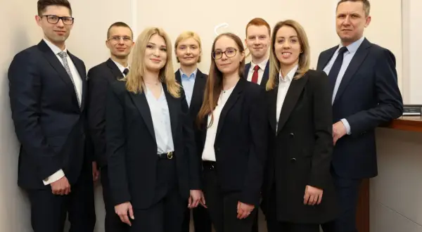 Grupa prawników w garniturach stoi w rzędzie, patrząc w stronę obiektywu.