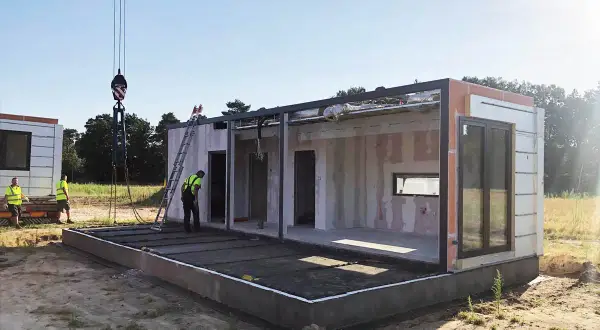 Budowa modułowego budynku, zgodna z art. 29 prawa budowlanego. Dźwig podnosi element konstrukcyjny.