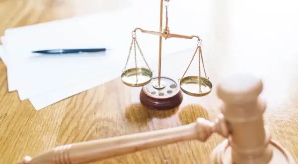 Młotek sędziowski, waga sprawiedliwości i dokumenty. Gdy słyszymy "odroczenie rozprawy co to znaczy", myślimy o tym, że sprawa będzie kontynuowana później.