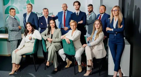Zespół prawników w garniturach pozuje do zdjęcia w nowoczesnym biurze.