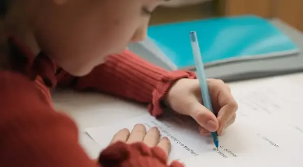 Dziecko pisze test, starając się o dopuszczający ocena.
