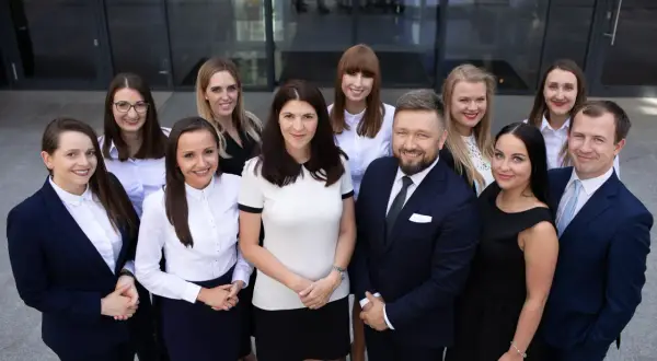 Grupa prawników w garniturach i strojach biznesowych pozuje przed budynkiem.
