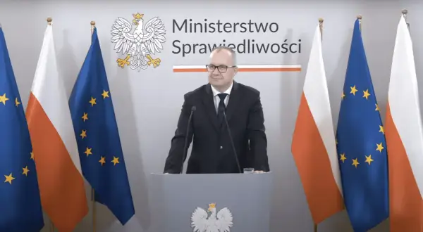 Minister sprawiedliwości przemawia na tle flag Polski i UE. Tematem dyskusji jest ustawa frankowa.